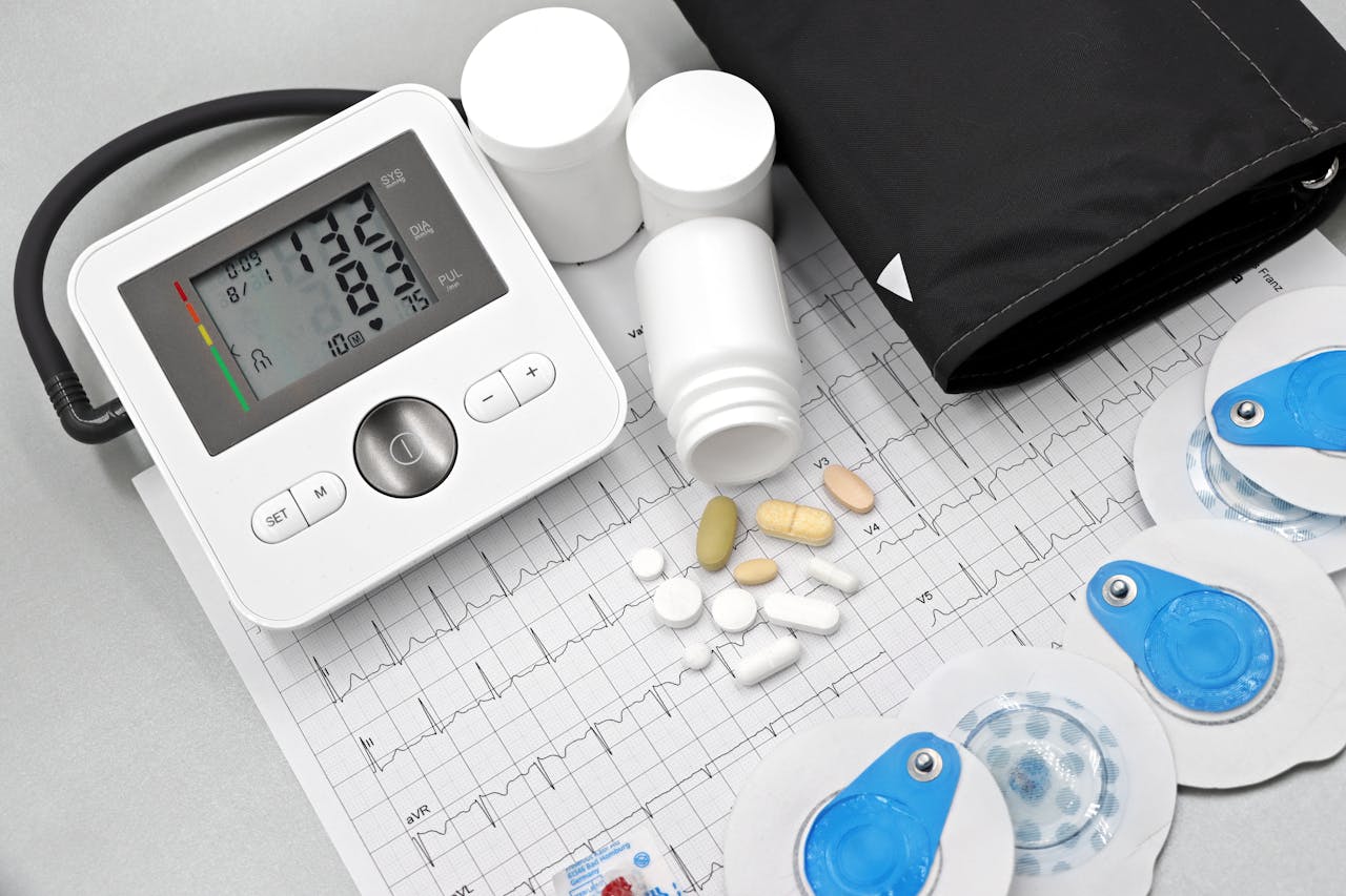 gallery-5 Flat lay of blood pressure monitor, pills, and ECG printout for heart health theme.