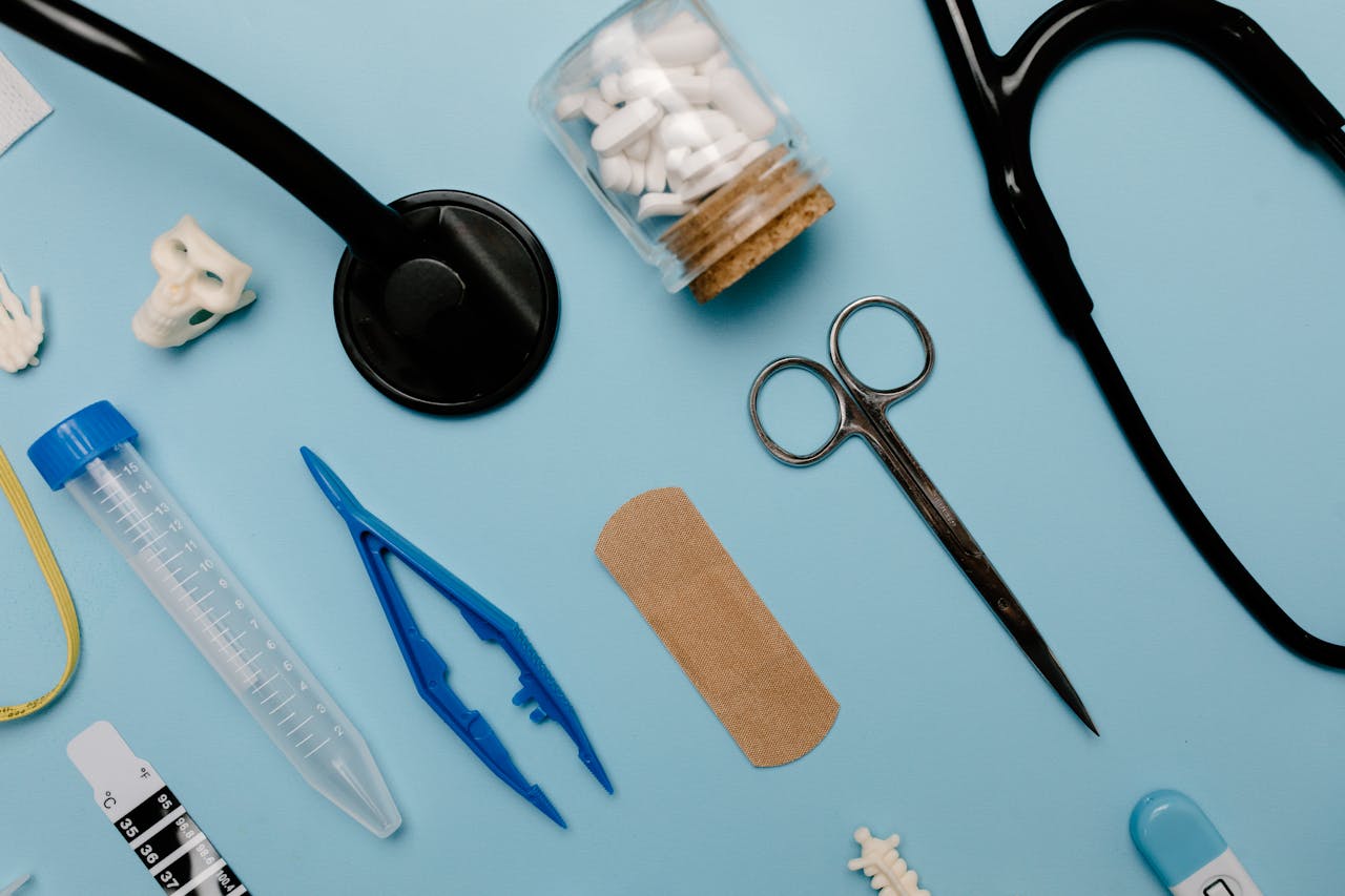 gallery-1 Flat lay of assorted medical tools and equipment on a blue surface.